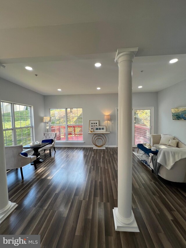 living room featuring ornate columns, a healthy amount of sunlight, and dark hardwood / wood-style floors