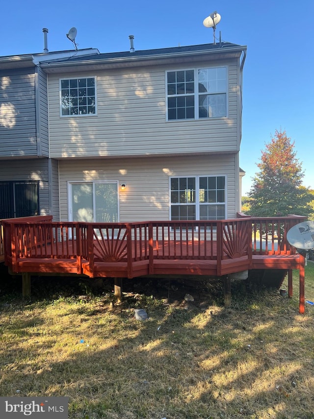 back of property featuring a wooden deck and a yard