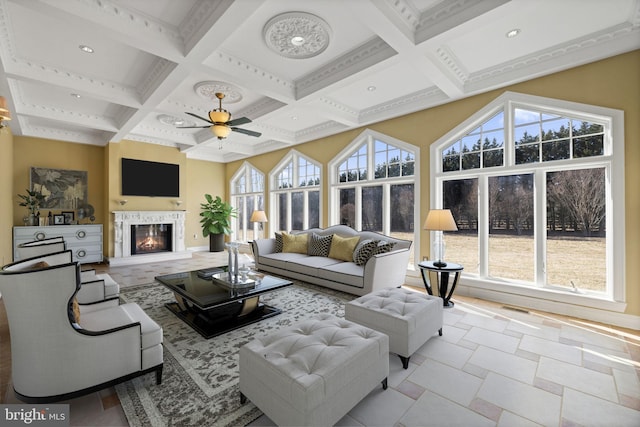 living room with plenty of natural light, coffered ceiling, beamed ceiling, and a glass covered fireplace