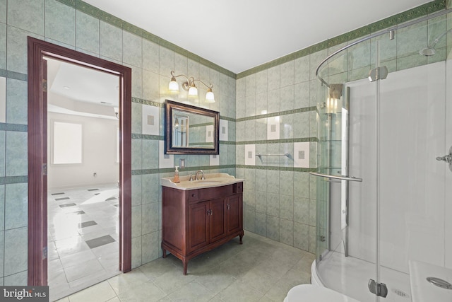 full bath with tile patterned floors, tile walls, a shower stall, and vanity