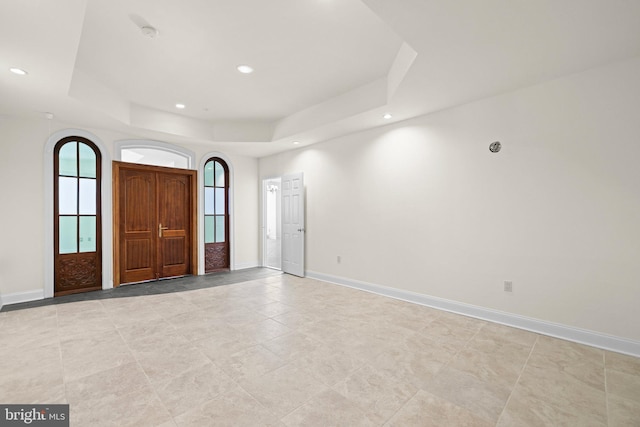 foyer entrance with recessed lighting, a raised ceiling, and baseboards