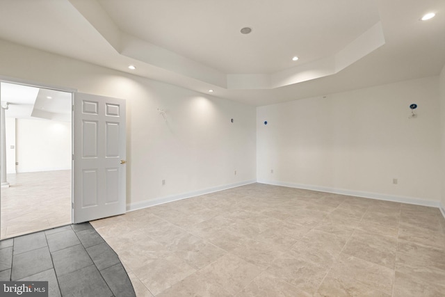 empty room with a tray ceiling, baseboards, and recessed lighting