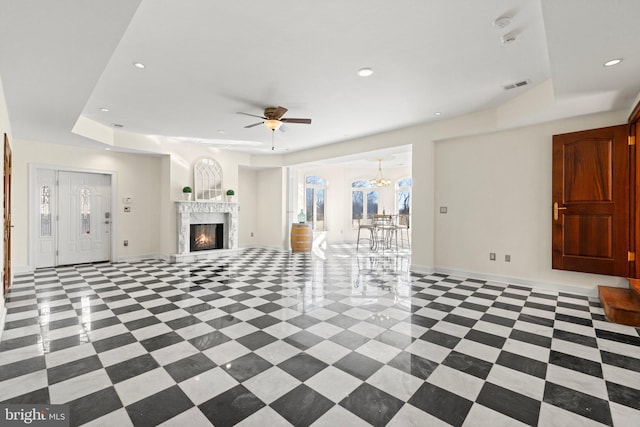 unfurnished living room with baseboards, a tray ceiling, visible vents, and recessed lighting