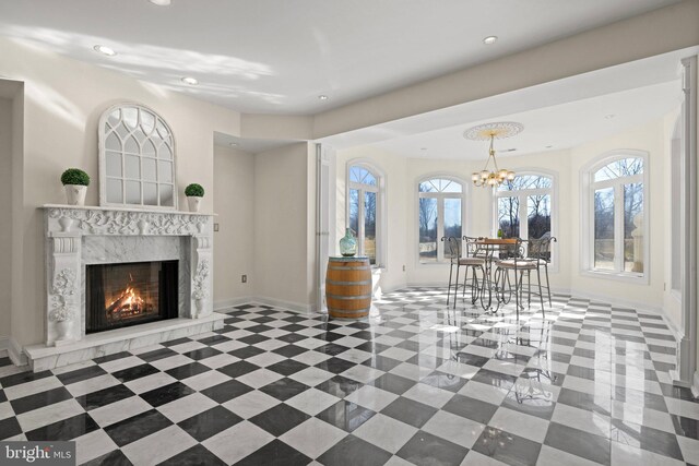 interior space featuring baseboards, recessed lighting, a high end fireplace, and an inviting chandelier