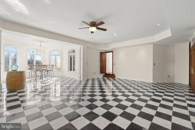 unfurnished living room with recessed lighting, a raised ceiling, baseboards, and ceiling fan with notable chandelier