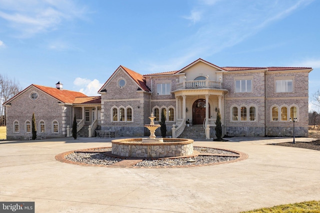 view of front of home with a balcony and curved driveway