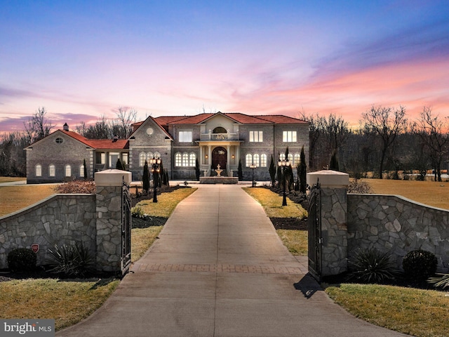 view of front facade featuring concrete driveway, a fenced front yard, a gate, and a balcony