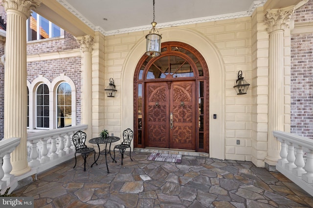 view of exterior entry featuring a porch and brick siding