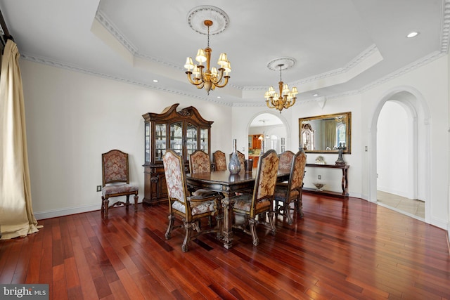 dining room featuring arched walkways, a tray ceiling, hardwood / wood-style floors, and an inviting chandelier