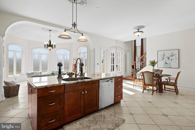 kitchen featuring light tile patterned floors, light stone counters, hanging light fixtures, stainless steel dishwasher, and a sink