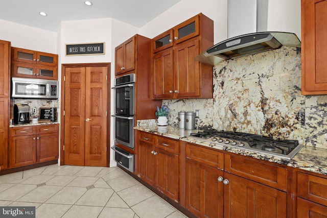 kitchen with glass insert cabinets, light stone counters, stainless steel appliances, ventilation hood, and a warming drawer