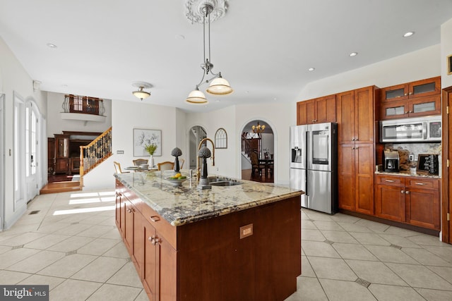 kitchen with arched walkways, stainless steel appliances, a sink, and light tile patterned flooring