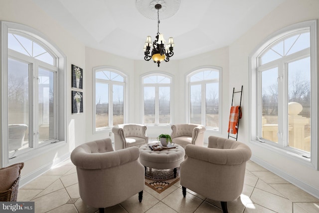 sunroom featuring a notable chandelier, a raised ceiling, and a wealth of natural light