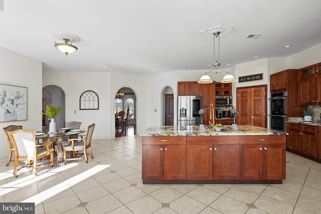 kitchen with light stone counters, arched walkways, pendant lighting, stainless steel appliances, and light tile patterned flooring