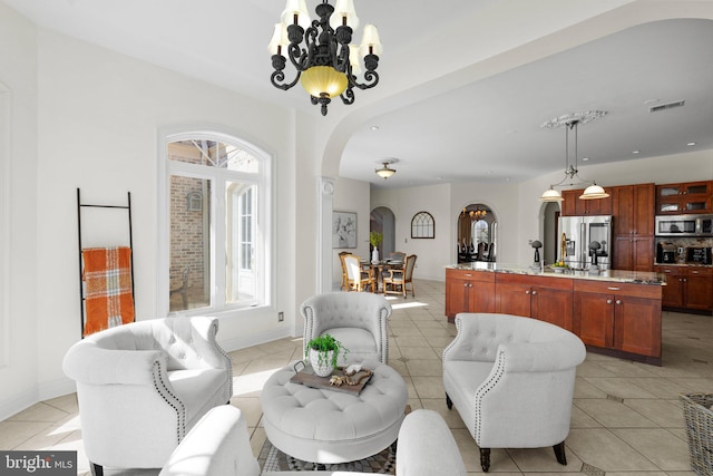 living area featuring arched walkways, visible vents, light tile patterned flooring, and an inviting chandelier