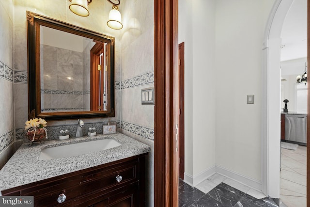 bathroom with marble finish floor, vanity, and baseboards