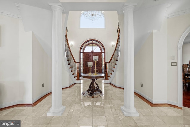 entrance foyer featuring arched walkways, decorative columns, stairway, and baseboards