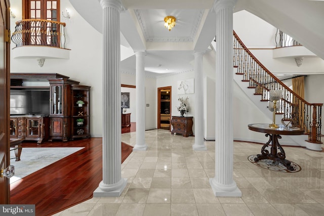 entryway featuring a towering ceiling, decorative columns, ornamental molding, and baseboards