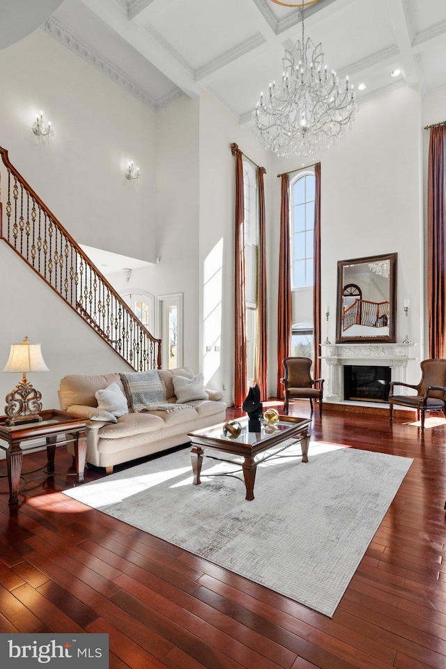 living area featuring dark wood-type flooring, a glass covered fireplace, a high ceiling, and stairs