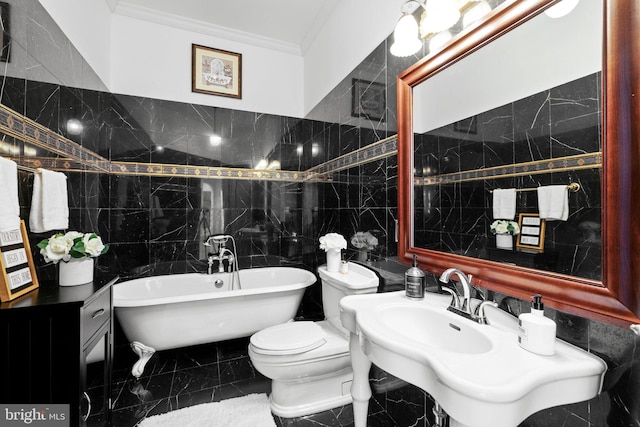 bathroom featuring a freestanding bath, marble finish floor, ornamental molding, and tile walls