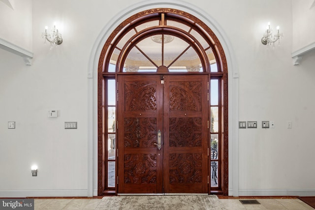 foyer featuring arched walkways, visible vents, a notable chandelier, and baseboards