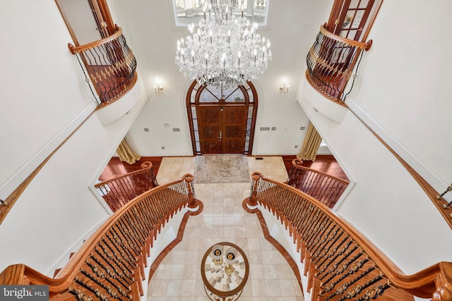 entryway featuring a wealth of natural light, a towering ceiling, an inviting chandelier, baseboards, and stairs