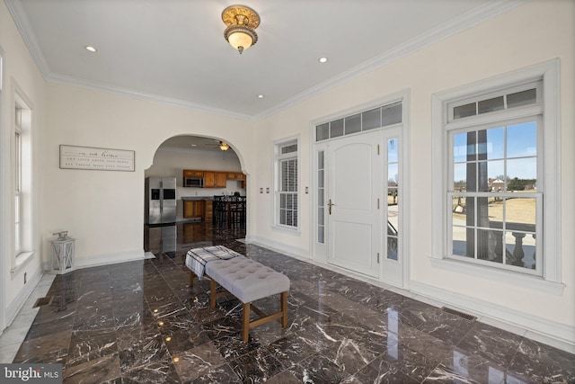 entrance foyer with arched walkways, marble finish floor, crown molding, and baseboards