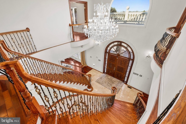 entrance foyer featuring visible vents, arched walkways, wood finished floors, a high ceiling, and a notable chandelier