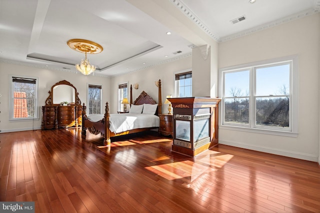 bedroom with visible vents, a raised ceiling, baseboards, wood-type flooring, and a notable chandelier