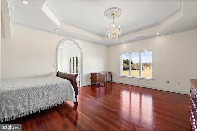 bedroom featuring a notable chandelier, baseboards, a raised ceiling, and hardwood / wood-style floors