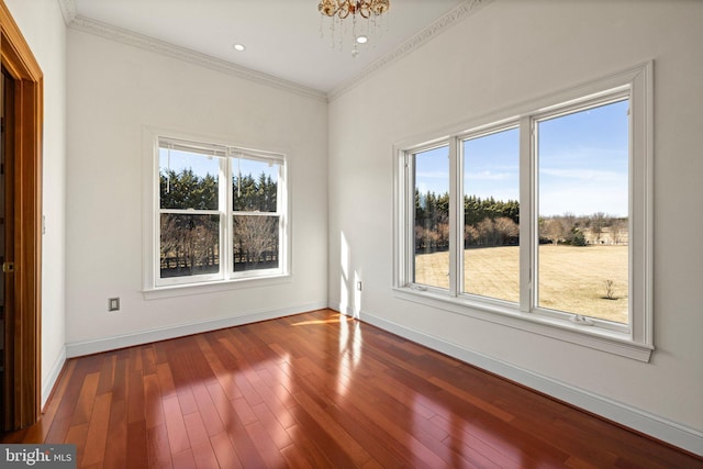 unfurnished room featuring plenty of natural light, baseboards, hardwood / wood-style floors, and ornamental molding