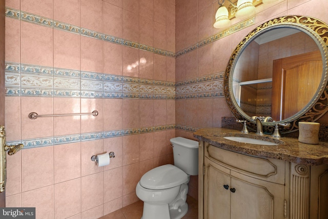 bathroom with vanity, toilet, and tile walls