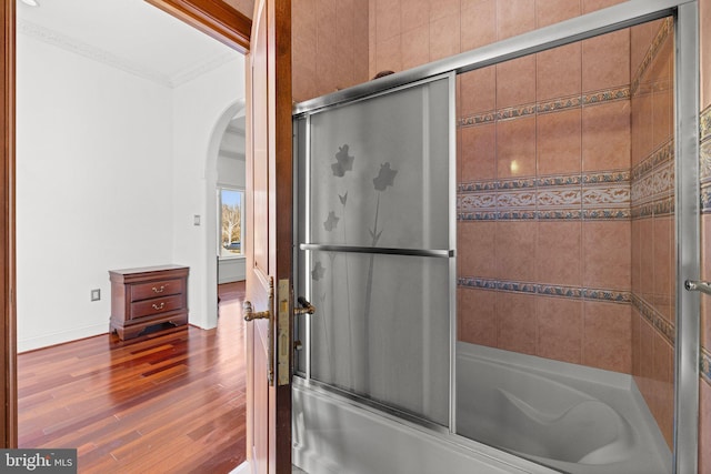 full bath featuring ornamental molding, enclosed tub / shower combo, baseboards, and wood finished floors