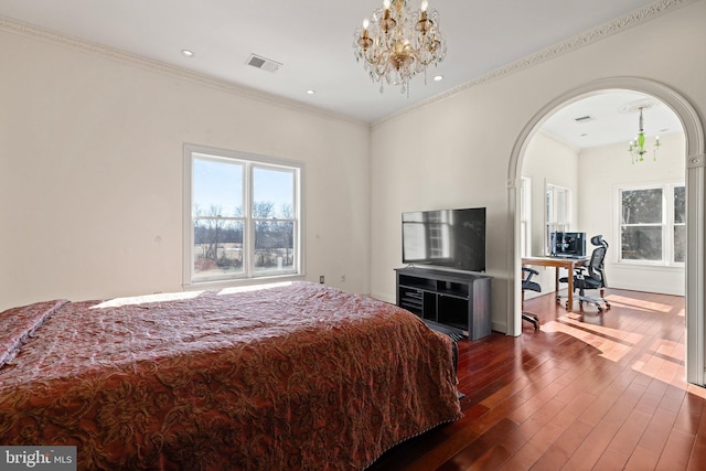 bedroom featuring arched walkways, dark wood-style flooring, visible vents, and an inviting chandelier