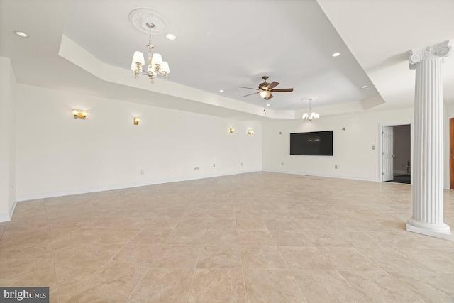 unfurnished living room with ceiling fan with notable chandelier, a tray ceiling, baseboards, and ornate columns