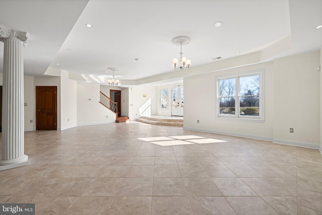 unfurnished living room with recessed lighting, a notable chandelier, baseboards, and decorative columns