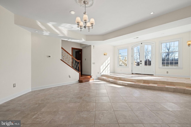 entrance foyer with baseboards, stairway, plenty of natural light, and an inviting chandelier