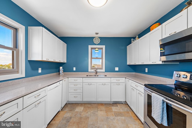 kitchen with sink, appliances with stainless steel finishes, decorative light fixtures, and white cabinets