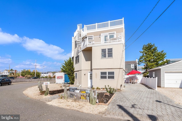 view of front of property with an outdoor structure, a garage, and a balcony