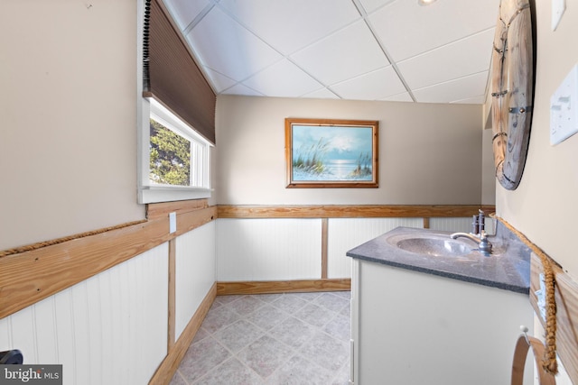 bathroom with vanity, wood walls, and a paneled ceiling