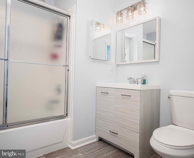 full bathroom featuring vanity, toilet, combined bath / shower with glass door, and hardwood / wood-style flooring