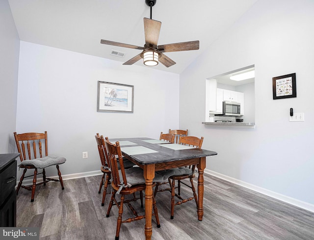 dining room with dark hardwood / wood-style floors, high vaulted ceiling, and ceiling fan