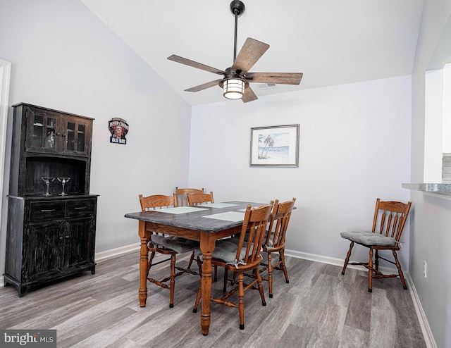 dining room featuring ceiling fan, light wood-type flooring, and high vaulted ceiling