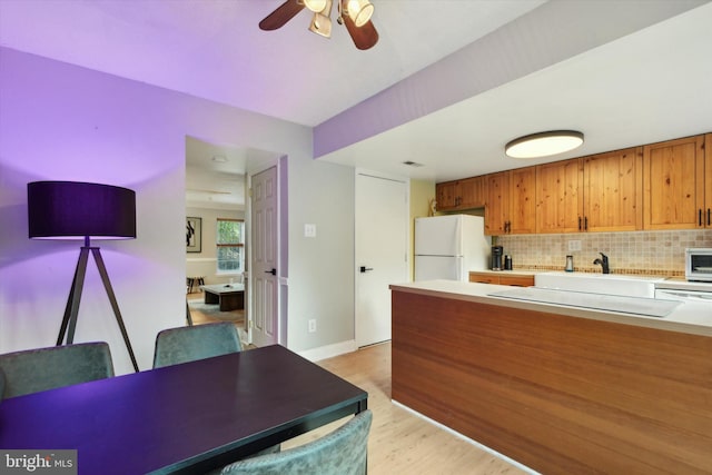 kitchen with white appliances, tasteful backsplash, sink, light hardwood / wood-style floors, and ceiling fan