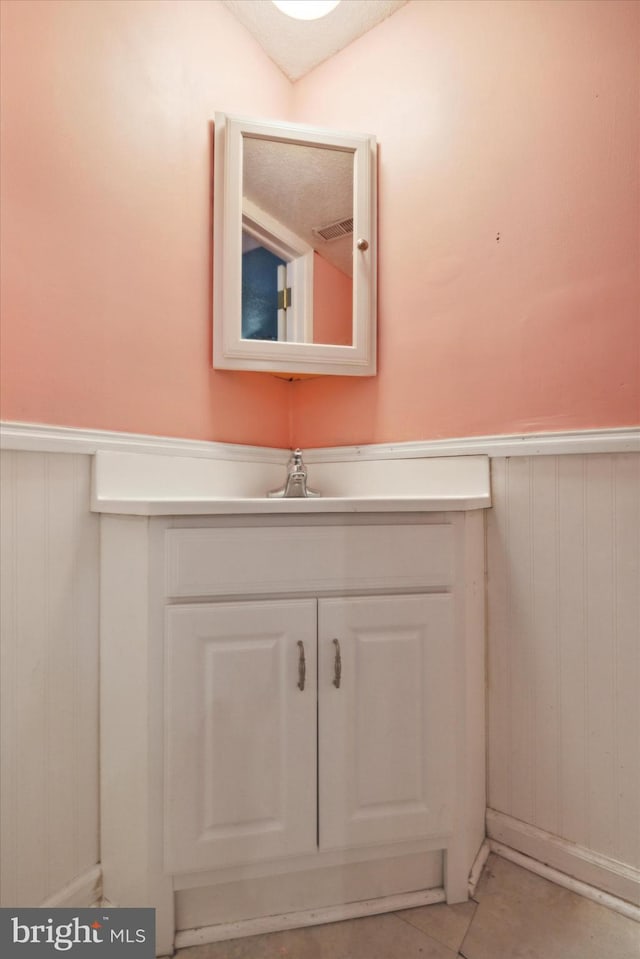 bathroom with vanity, vaulted ceiling, and wood walls