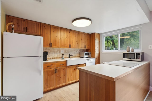 kitchen featuring sink, decorative backsplash, light wood-type flooring, and white appliances