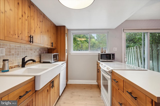 kitchen with sink, light hardwood / wood-style flooring, white appliances, and tasteful backsplash