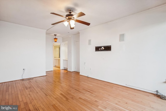 spare room featuring a ceiling fan, baseboards, ornamental molding, and light wood finished floors