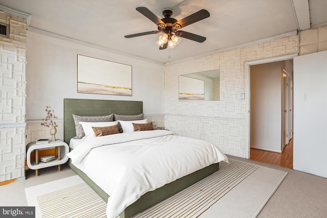 carpeted bedroom featuring a ceiling fan, a wainscoted wall, and crown molding