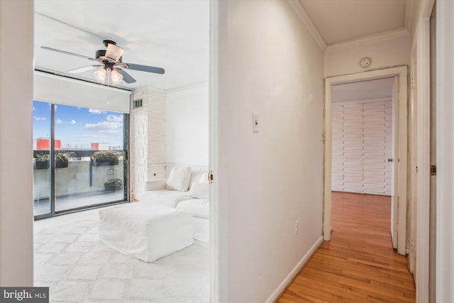 corridor with light wood-type flooring, baseboards, visible vents, and ornamental molding